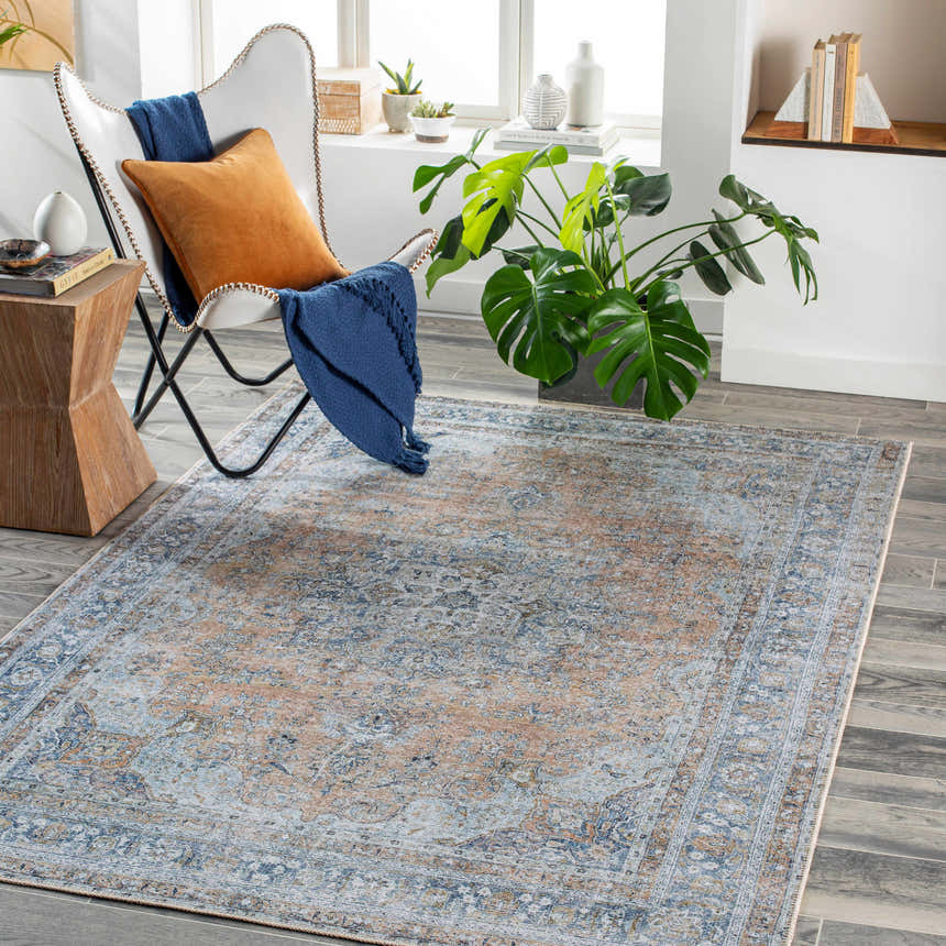 Living room with a white chair and the Mianay Washable Area Rug in beige, blue, and light gray. Roomscene-Rectangle