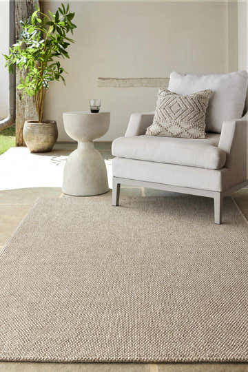 Outdoor patio scene with a Matah Beige Outdoor Area Rug, chair, side table, and potted plant. Roomscene-Rectangle
