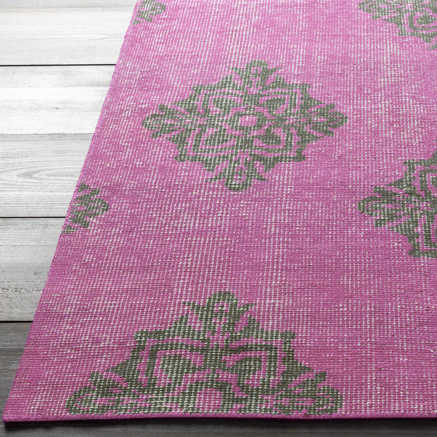 Close up of the fuchsia Mina Area Rug showing its hand knotted wool texture and black geometric pattern. Front