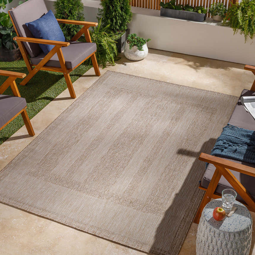 Outdoor patio scene with tan Manorhaven Indoor & Outdoor Rug, wood chairs, and potted plants. Roomscene-Rectangle