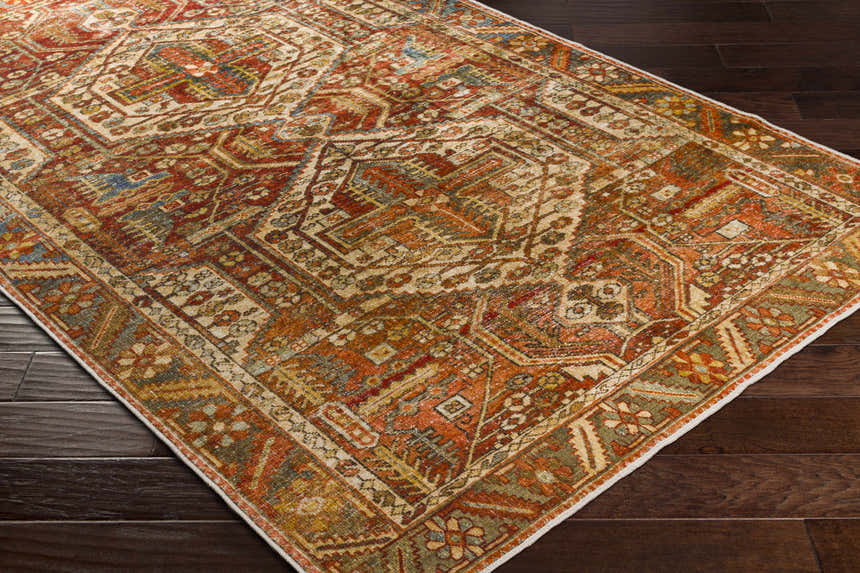 Close-up of the Mantalongon Washable Area Rug. Features a traditional, bohemian pattern in brick red, brown, and sage. Corner