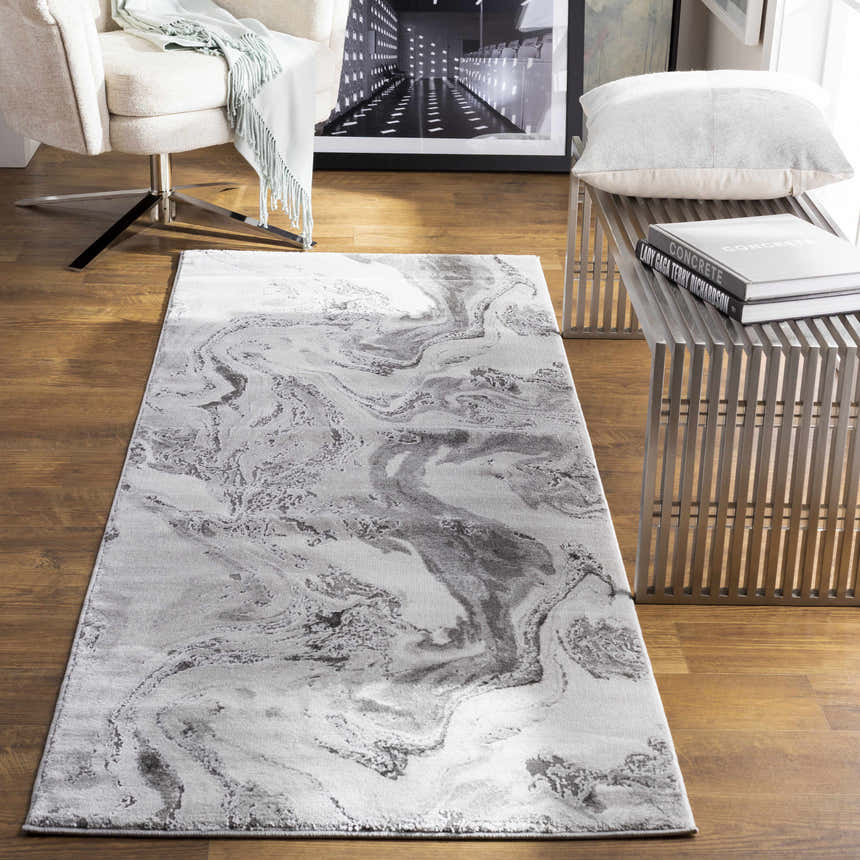 Modern living room scene with a charcoal marble Moana rug, white chair, and metal bench. Roomscene-Runner