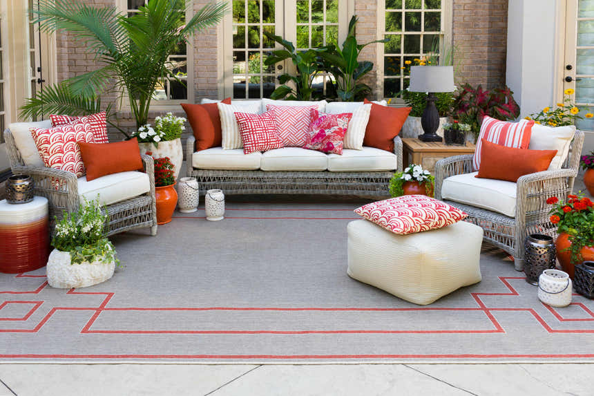 Brick red and beige Moffett Area Rug on a patio with wicker furniture and potted plants. Styleshot