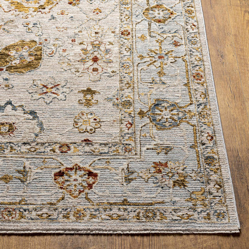 Close-up of the Mogul Luxe Oushak Rug. Features brick red, cream, denim, mustard, and tan floral pattern on a light gray background. Front