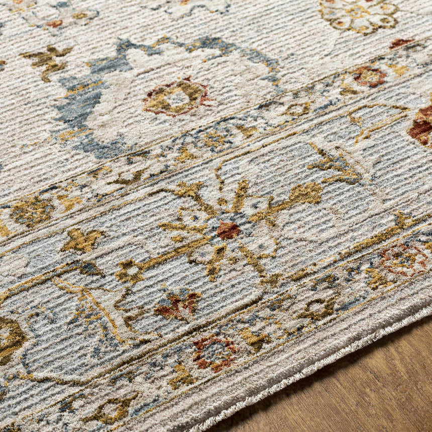 Close-up of the Mogul Luxe Oushak Rug. Features a traditional floral pattern in cream, denim, mustard, and brick red tones. Texture