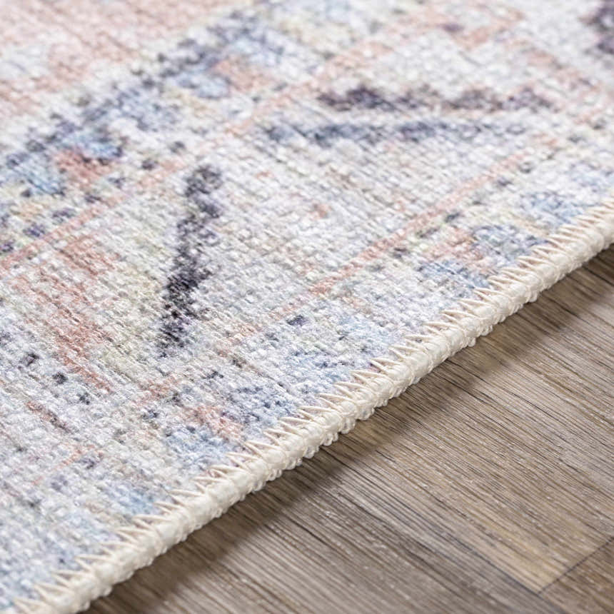Close-up of Morcott Peach Washable Area Rug, showing chenille-polyester texture and bohemian-inspired pattern in peach, blue, and ivory. Texture