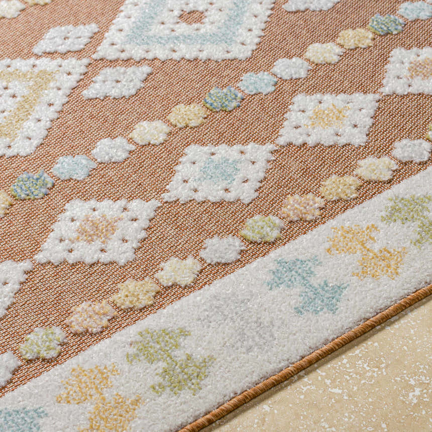 Close-up of Metta Rust Area Rug showing rust, cream, blue, and green geometric coastal pattern and textured weave. Texture