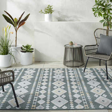 Coastal patio with Metta Medium Green Area Rug, woven chairs, and potted plants. Relaxing outdoor space. Roomscene-Rectangle