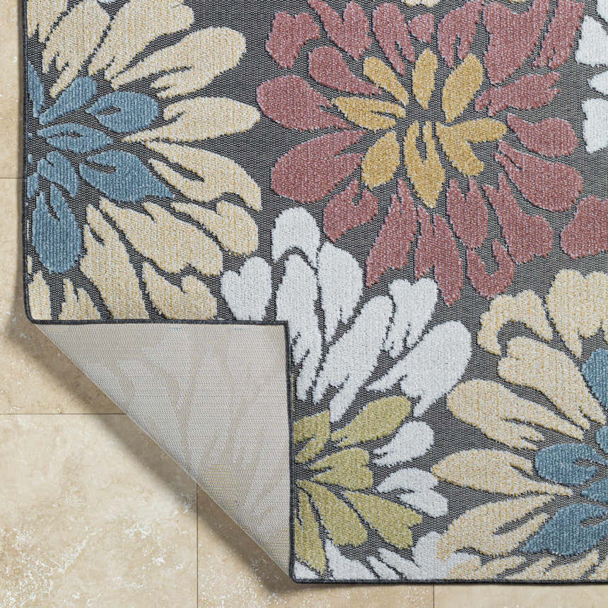 Close-up of Minga Charcoal Area Rug, showcasing its floral pattern in charcoal, cream, navy, olive, and rust hues. Machine woven texture. Fold