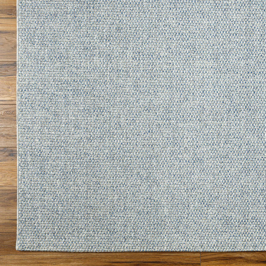 Close-up of the Mirit Area Rug showing a woven texture in denim and light gray on a wood floor. Swatch