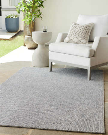 Outdoor patio scene with a light gray Mirit Area Rug, white chair, and potted plants. Roomscene-Rectangle
