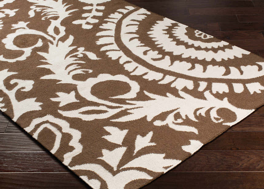 Close-up of the Naeva Area Rug, a hand-woven wool rug in dark brown and white with a contemporary floral pattern. Corner