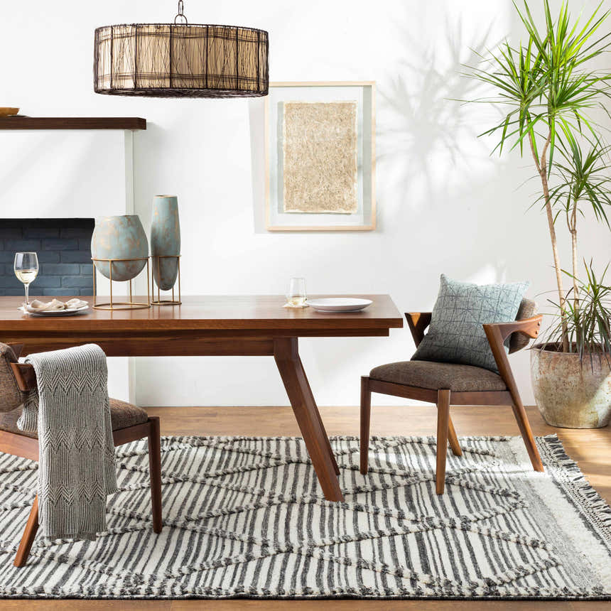 Dining room scene with a wood table and the black and ivory striped Nairobi Area Rug. Roomscene-Rectangle