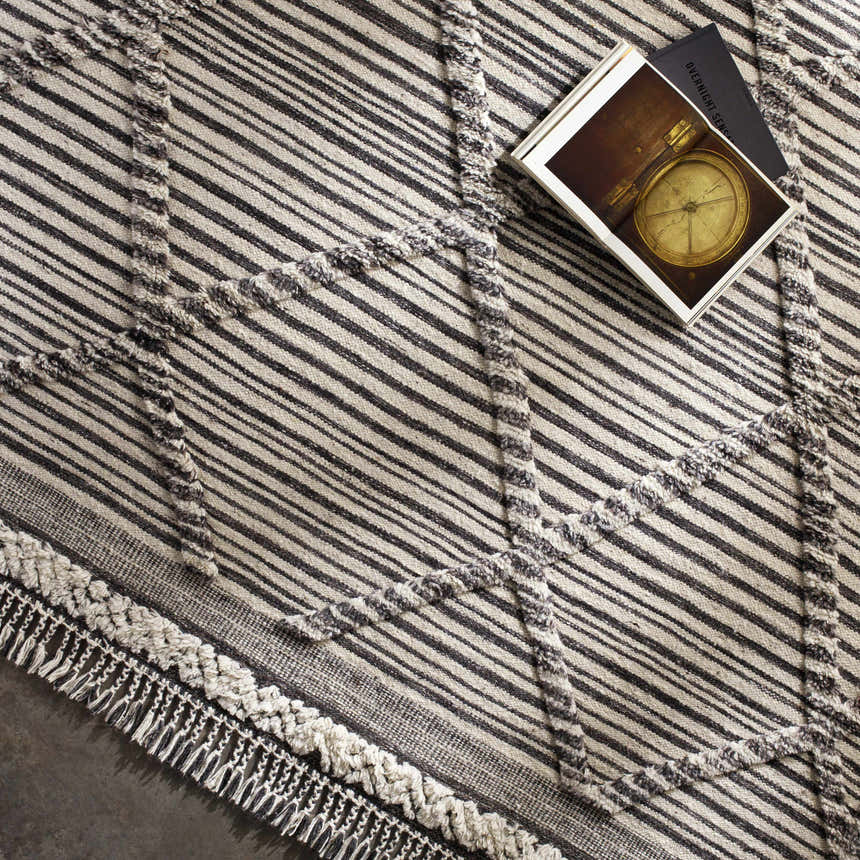 Close-up of the Nairobi Area Rug, a hand-knotted wool rug with black, gray, and ivory stripes and geometric accents. Styleshot