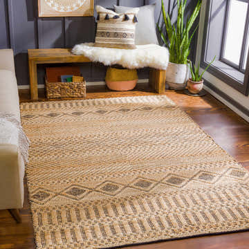 Living room scene with tan Nasugbu Jute Carpet. Bohemian rug with geometric pattern, tan sofa, and wood bench. Roomscene-Rectangle
