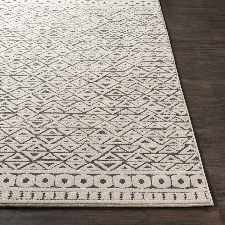 Close-up of Naylor Beige/Charcoal Rug showing geometric triangle pattern and border detail on dark wood floor. Front