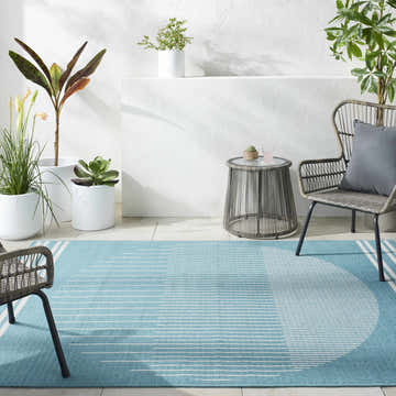 Stylish patio scene with aqua Nabil Area Rug, gray wicker furniture, and potted plants against a white wall. Roomscene-Rectangle