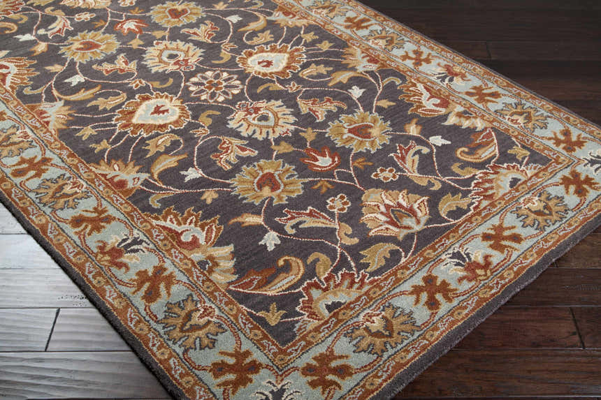 Close-up of the hand-tufted Cherryfield 1004 wool area rug. Features a floral pattern in beige, burnt orange, and slate blue. Corner