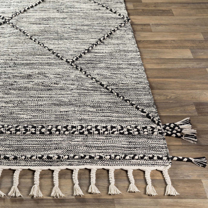 Close-up of Neal Black/Cream Trellis Cotton Rug with Tassels showing texture, trellis pattern, and braided tassel detail. Front