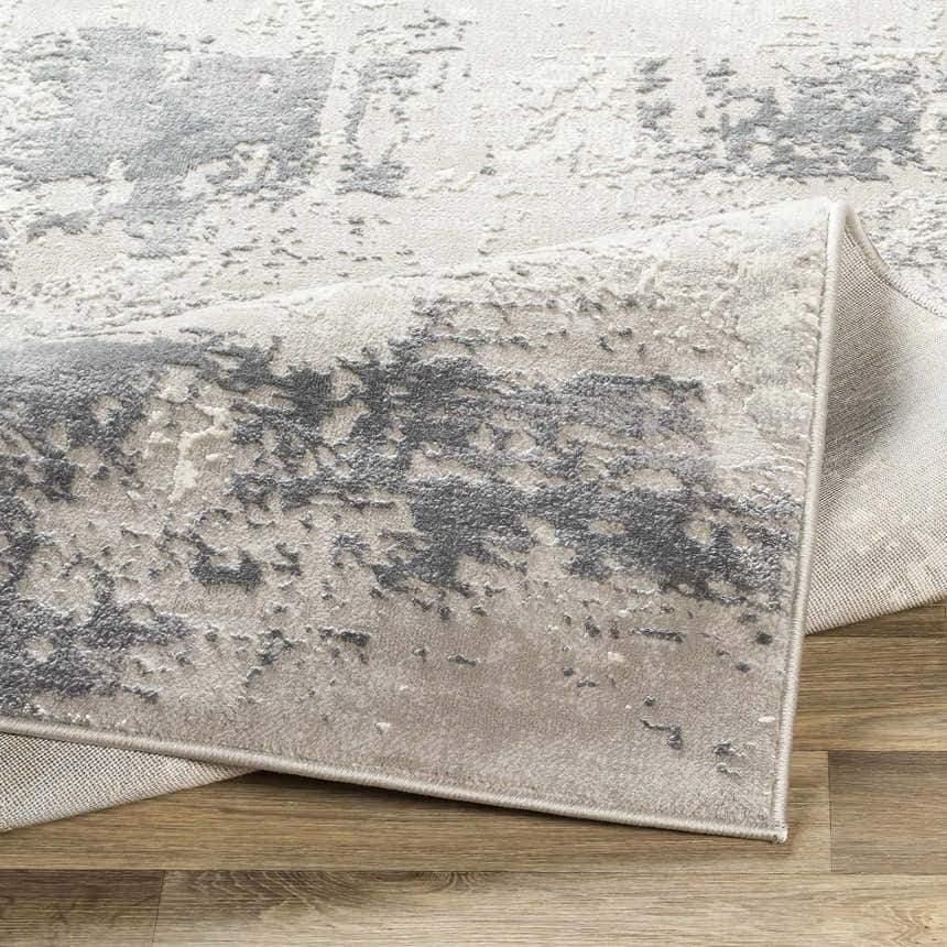 Close-up of the Neponsit Area Rug, showcasing its charcoal, gray, and ivory contemporary design and soft texture. Fold