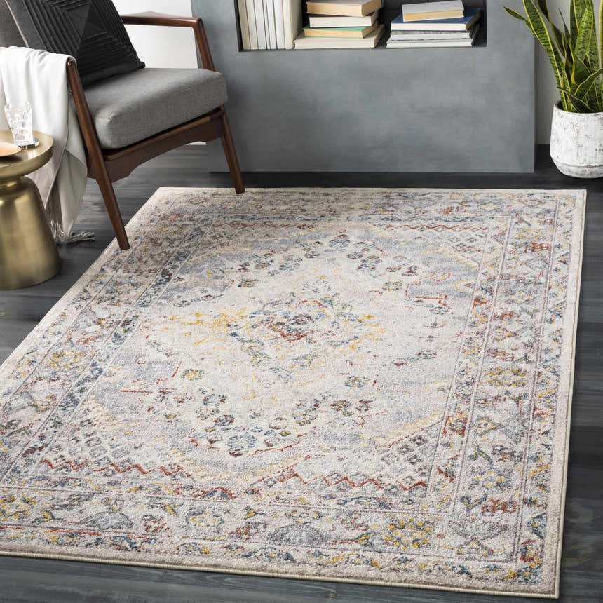 Living room scene with a Newkirk Area Rug in cream, brick red, and blue, styled with a mid-century chair and gold side table. Roomscene-Rectangle