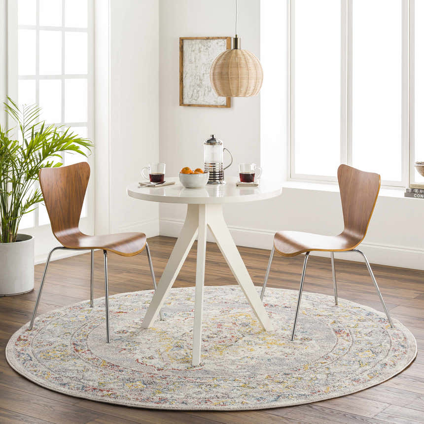 Bright breakfast nook with round white table and Newkirk Area Rug in cream, brick red, and blue. Roomscene-Round