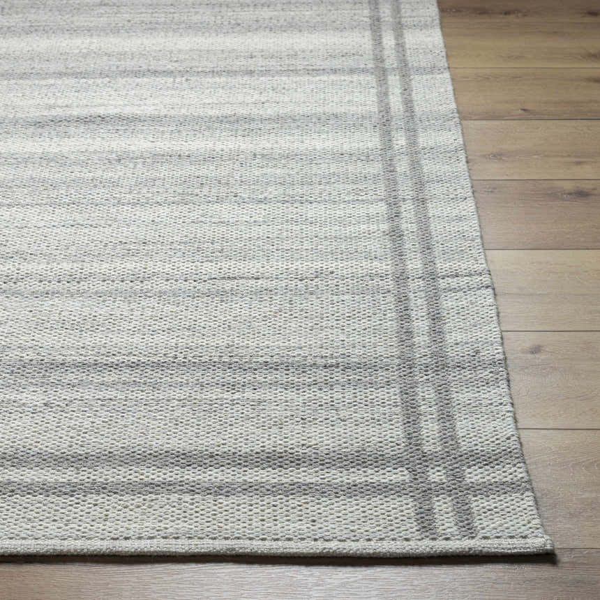 Close-up of the hand woven Nimue Gray Area Rug showing wool texture and gray striped design on wood floor. Front