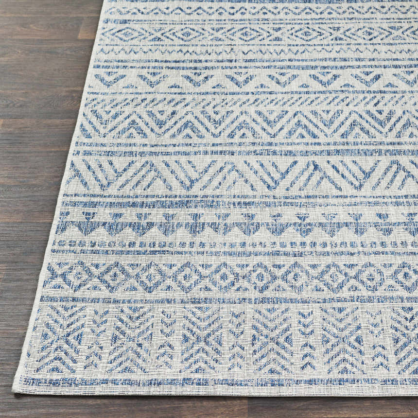 Close-up of the Novato All Over Pattern Performance Rug, showcasing its blue geometric design and woven texture on dark wood floor. Front