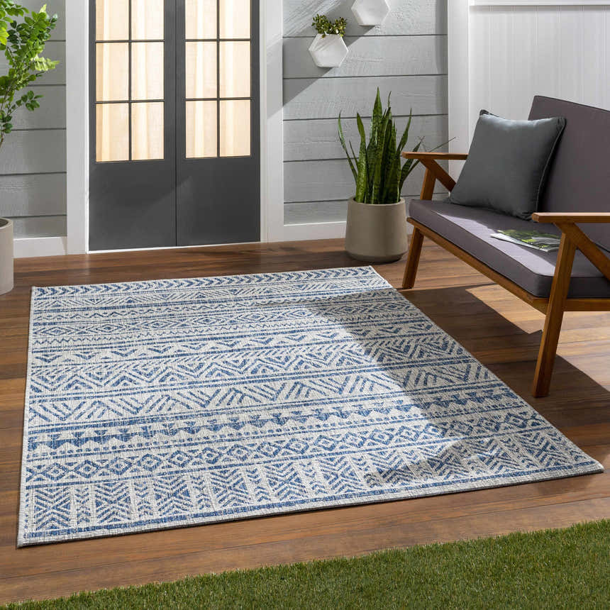 Outdoor patio scene with blue Novato All Over Pattern Performance Rug, gray loveseat, wood floor, and potted plants. Roomscene-Rectangle
