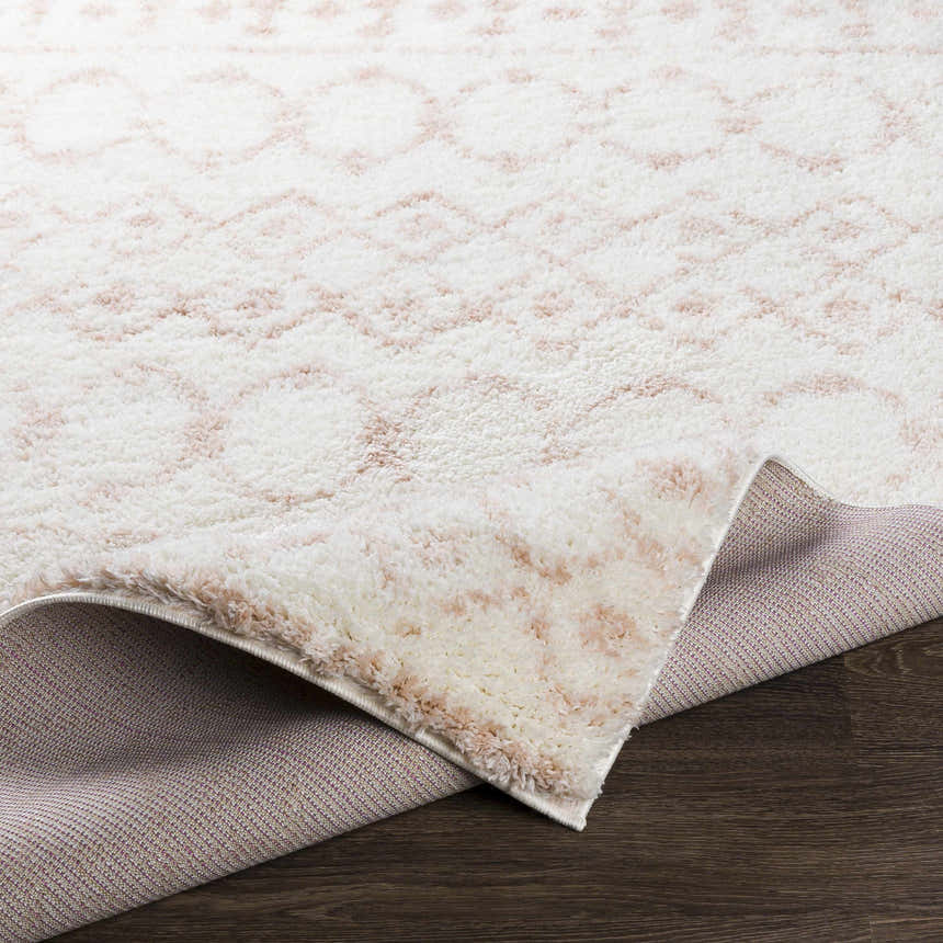 Close-up of the Narrogin Area Rug, blush and cream shag rug with a geometric pattern, showing the rug's backing. Fold