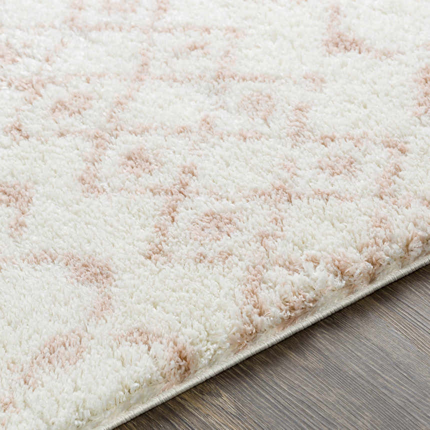 Close up of the plush Narrogin Area Rug with a blush and cream geometric pattern. Texture