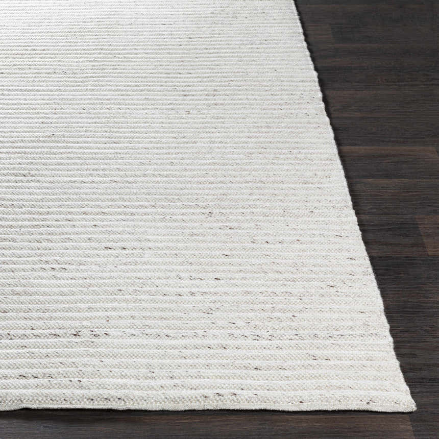 Close up of the hand woven Nuangola Area Rug in off white and dark brown on a dark wood floor. Front