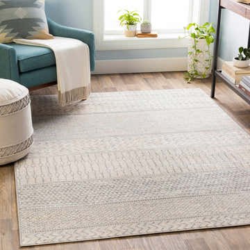 Living room scene with a Nunda Gray rug, teal chair, ivory ottoman, and wood floors. Contemporary style. Roomscene-Rectangle