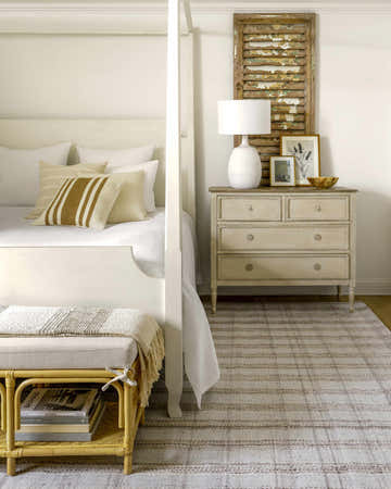 Bedroom scene with Becki Owens Sammy Brown Plaid Area Rug, white bed, tan pillows, and neutral dresser with lamp and decor. Roomscene-Rectangle