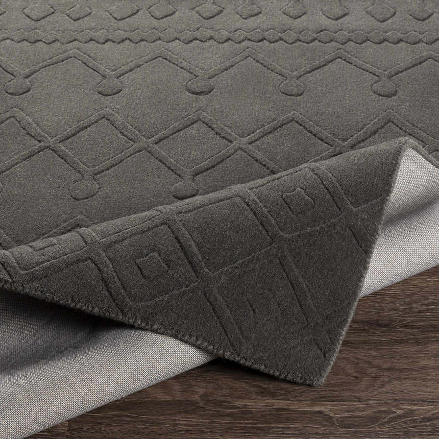Close-up of the charcoal Newtonhill Clearance Rug, a hand-loomed wool rug with a farmhouse-style geometric pattern. Fold