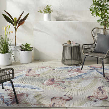 Coastal patio scene with Nayan Light Slate Area Rug featuring flamingo and palm leaf design. Wicker furniture and potted plants. Roomscene-Rectangle