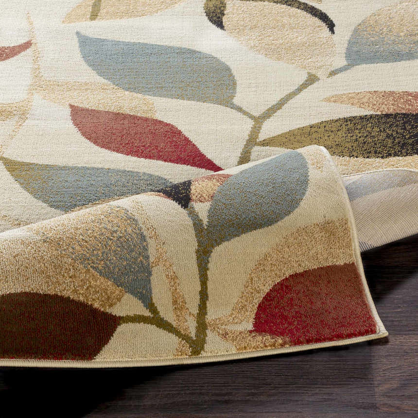 Close up of the Ober Fall Leaves Rug showing its leaf pattern and colors like red, blue, brown, and green. Fold