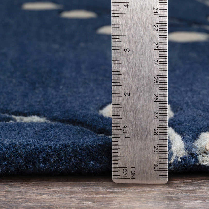 Close up of the ink blue Elsu Area Rug showing wool texture and pile height with a ruler for scale. Pile
