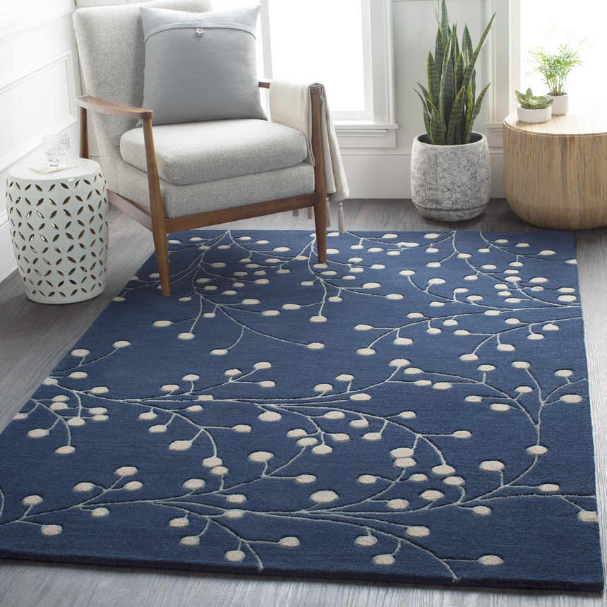 Living room scene with a Blue Elsu Area Rug, gray chair, and plants creating a cozy, transitional style. Roomscene-Rectangle