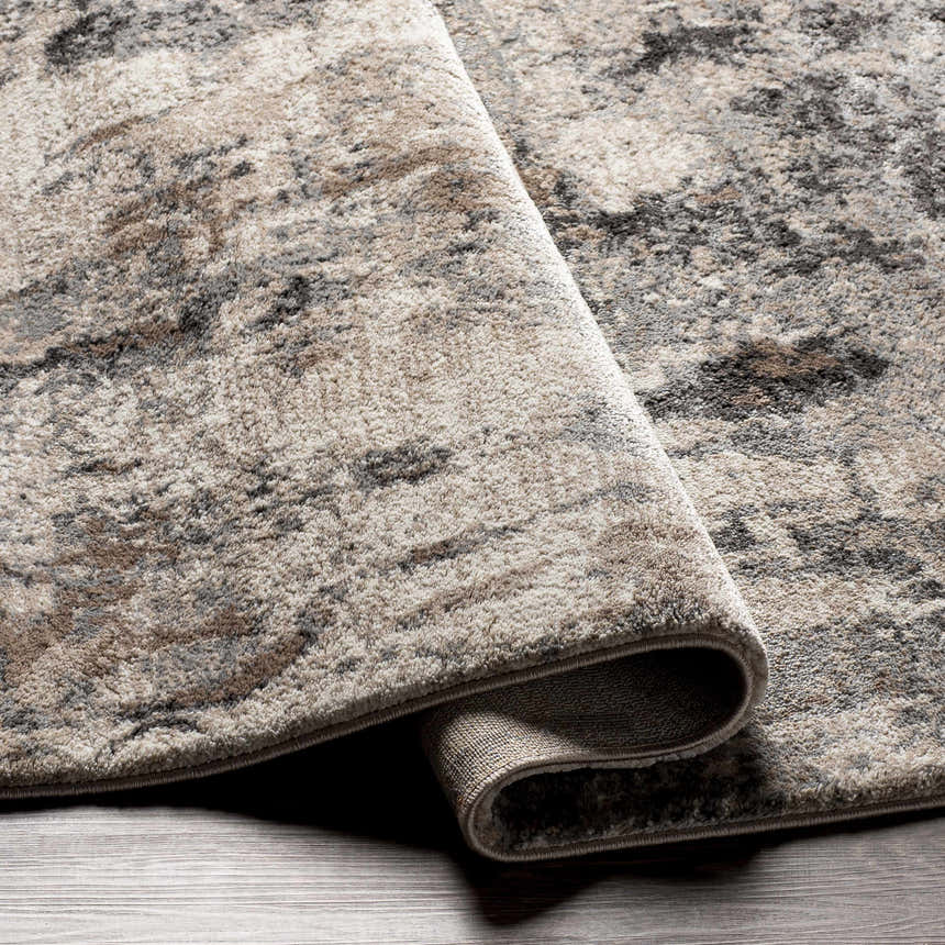 Close up of the Opunake Luxe Thick Area Rug showing its charcoal, cream, and brown abstract pattern and thick texture. Fold