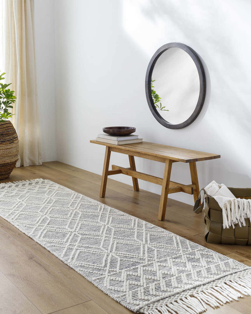 Entryway scene with a geometric cream and black Ossun Wool Rug runner, wood bench, round mirror, and woven basket. Roomscene-Runner