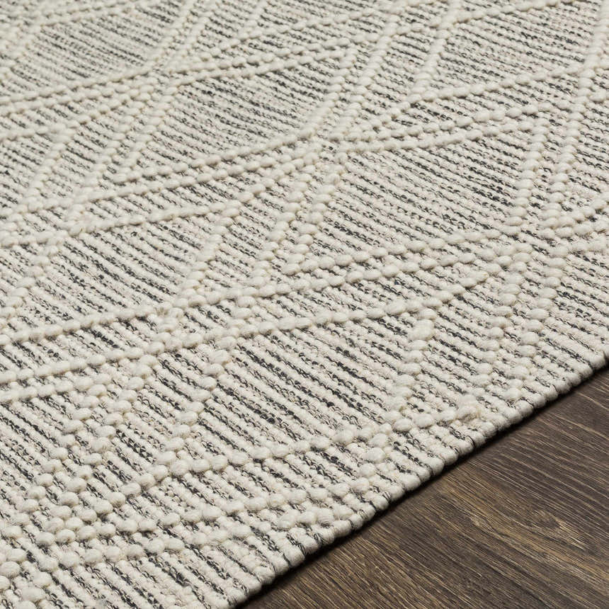 Close-up of the hand woven Ossun Wool Rug. Cream and black geometric pattern with raised texture. Texture