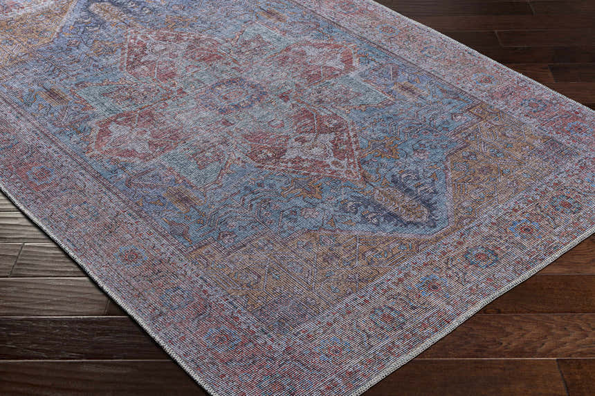 Close-up of the Otaki Washable Area Rug showing its traditional oriental pattern in dark gray, purple, brown, and natural gray tones. Corner