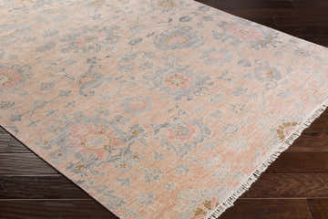 Close-up of the Pittston Area Rug. Beige, dusty coral, and charcoal floral pattern on a hand-knotted viscose rug. Corner