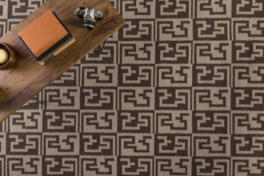 Close-up of the Paxville Area Rug, a hand-woven wool rug with a beige and dark red geometric pattern. Styleshot