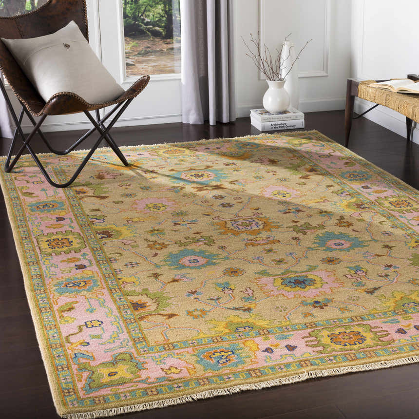Living room scene with a Peacham Area Rug, leather chair, and natural light. The rug has brown, pink, and blue floral patterns. Roomscene-Rectangle