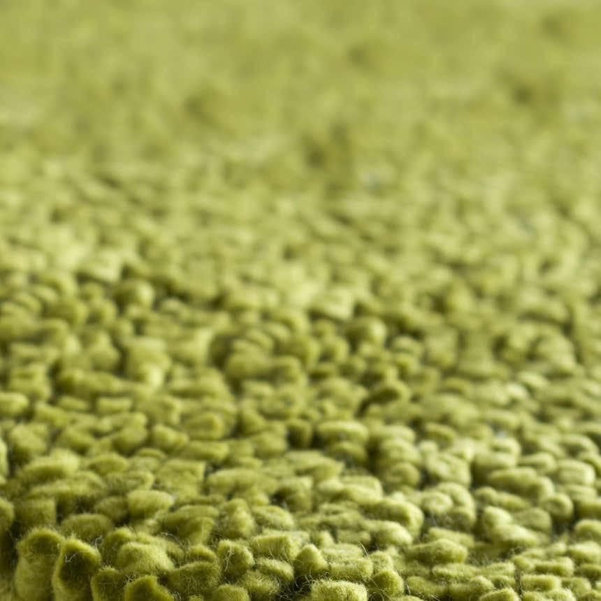 Close-up of the Frederika Solid Olive Green Wool Shag Rug showing its thick, textured wool fibers. Texture