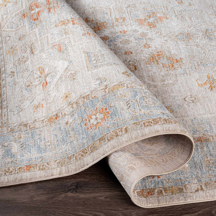 Close-up of rolled Phyllis Thick Luxe Statement Rug showing beige, blue, and orange traditional pattern and plush texture. Fold