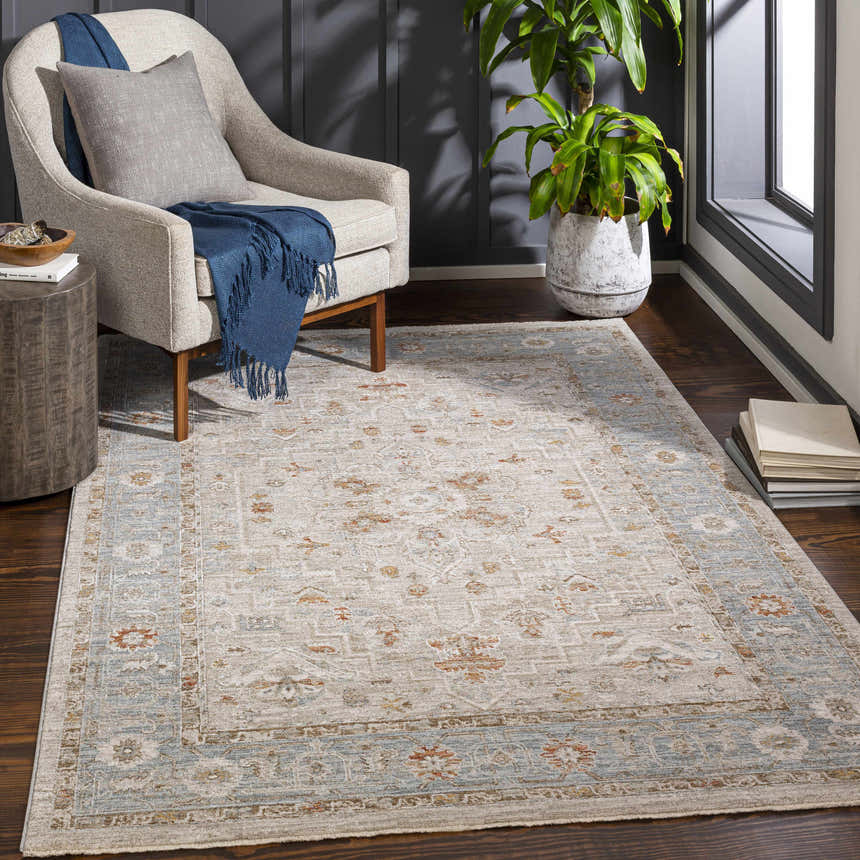 Living room scene with a Phyllis Thick Luxe Statement Rug, beige chair, wood floors, and a potted plant. Roomscene-Rectangle