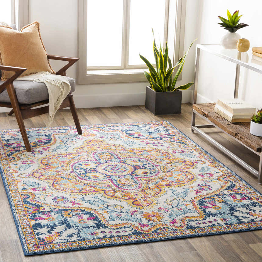Living room scene with Pimperne Traditional Medallion Area Rug in burnt orange, fuchsia, and navy. Bohemian style with wood chair. Roomscene-Rectangle
